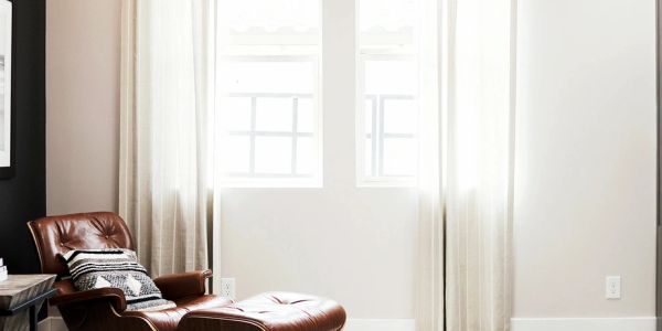Cozy corner with leather chair and natural light from windows.